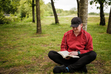 Obraz premium Man reading book relaxing in nature park
