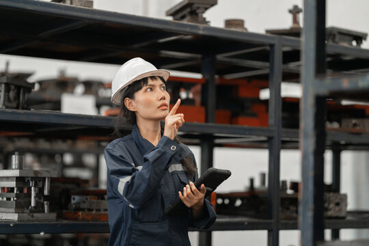 Industrial inspector woman examining metal parts in warehouse