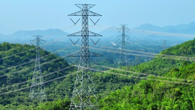Aerial landscape of high voltage electricity infrastructure across lush forests, showcasing national power transmission, green grid solutions, ESG responsibility, and sustainable energy management.
