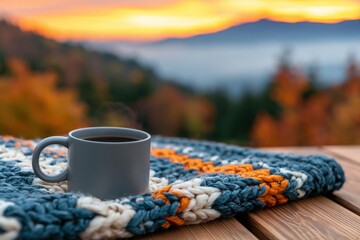 Fototapeta premium Coffee mug on a cozy knitted blanket with autumn mountain sunrise warmth view