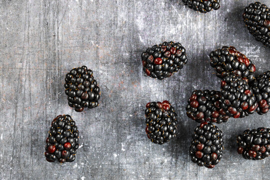 Fresh sweet blackberries scattered on a dark textured background