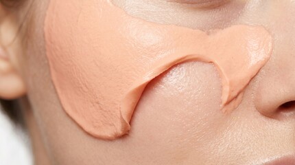 Fototapeta premium Macro close up of pink clay facial mask smeared on human cheek for pore cleansing