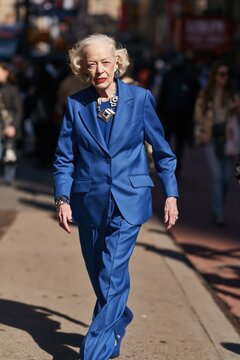 Elegant senior woman walking in city. Stylish elderly lady in blue suit outdoors.