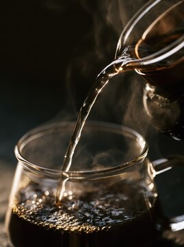 Hot coffee pouring into glass cup. Fresh morning beverage being served in a cafe.