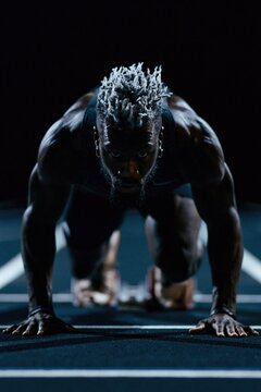 Sprinter in starting position on track. Athlete preparing for a race on running lane.