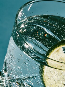 Glass of sparkling water with lime. Refreshing carbonated drink with citrus slice.