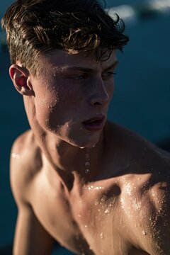 Wet young man portrait at the beach. Handsome guy with water droplets on skin.