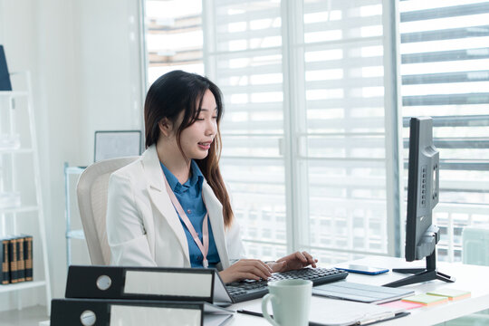 Young Businesswoman Working at Office Desk While Managing Documents and Mobile Communication.