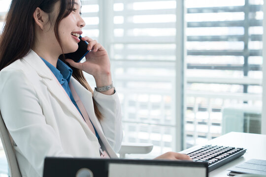 Young Businesswoman Working at Office Desk While Managing Documents and Mobile Communication.