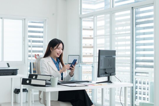 Young Businesswoman Working at Office Desk While Managing Documents and Mobile Communication.