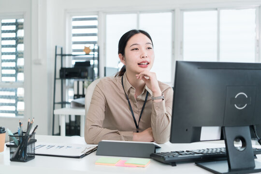Young Businesswoman Working at Office Desk While Managing Documents and Mobile Communication.