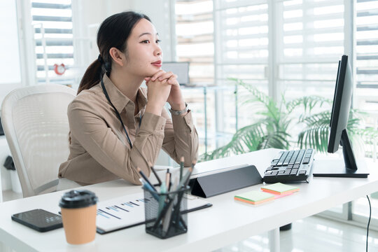 Young Businesswoman Working at Office Desk While Managing Documents and Mobile Communication.