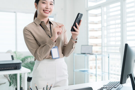 Young Businesswoman Working at Office Desk While Managing Documents and Mobile Communication.