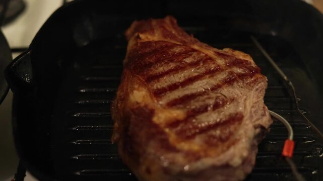 Juicy steak seared on a cast iron grill pan with temperature probe
