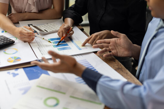 Business professionals discussing financial reports and charts during an office meeting, analyzing data for planning and strategy.