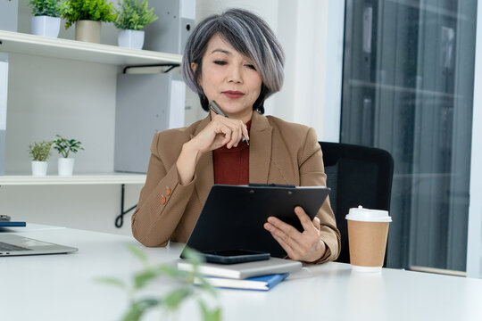 Businesswoman Reviewing Notes on Clipboard in Modern Office