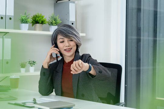 Businesswoman Checking Watch While on Phone Call in Office