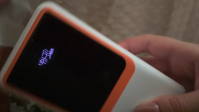 Person charging a colorful led string light garland with a modern portable power bank, using a built in usb port to power the festive and luminous home decoration