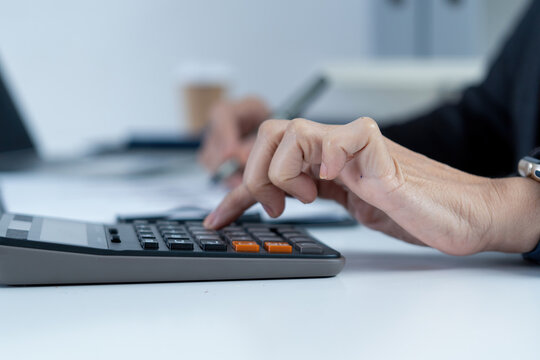 Macro Close Up of Businesswoman Hands Using Calculator at Office Desk