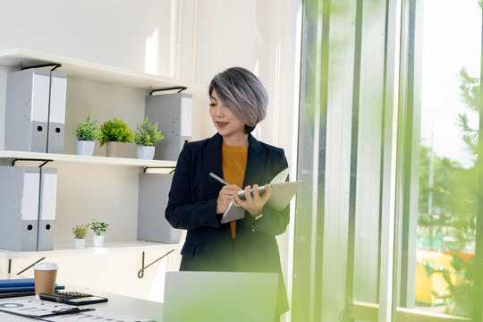 Businesswoman Standing and Writing Notes at Office Desk
