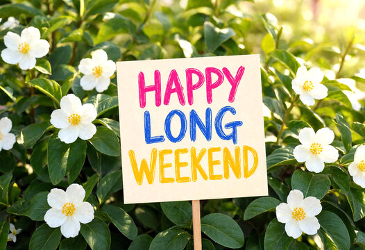 Colorful handwritten happy long weekend sign surrounded by blooming white flowers and green leaves