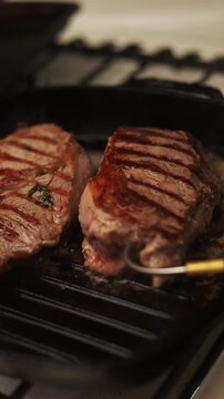 Juicy beef steaks sizzling on a cast iron grill pan with herbs