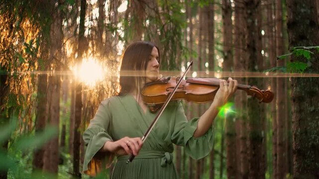 Woman in flowing green dress playing violin in tranquil forest, bathed in warm golden sunset light filtering through tall trees and peaceful natural surroundings
