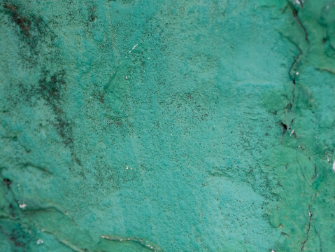 Close-up of a weathered, textured turquoise wall surface with peeling paint, cracks, and vintage patina, Gamcheon Culture Village Busan.
