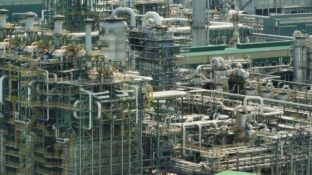 Aerial panorama of a giant refinery facility displaying complex industrial architecture, advanced chemical processing technology, and the challenge of decarbonizing traditional fossil energy systems.
