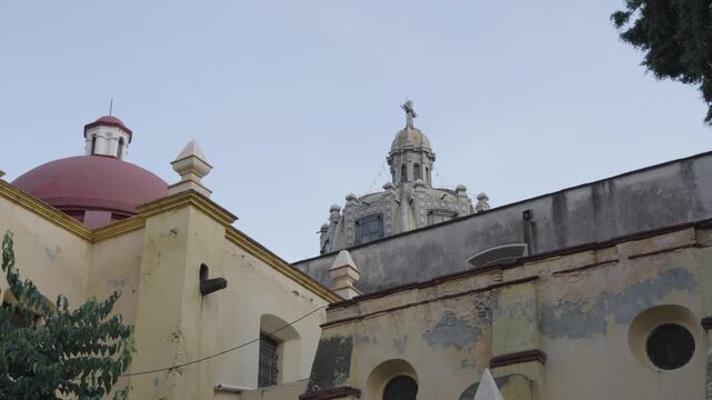 Old weathered facade of the san juan bautista parish church with its domes in coyoacan, mexico city