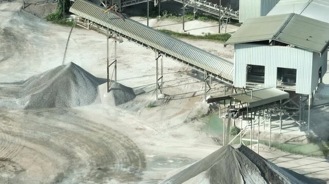 A crushed rock transported by conveyor systems at a quarry site, illustrating mechanical precision, bulk material processing, industrial workflow, and environmental challenges from dust emissions.
