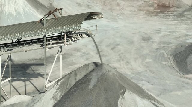 High-angle aerial capture of aggregate conveyor systems transferring crushed stone into storage piles, representing industrial production flow, mechanical engineering, and infrastructure development.
