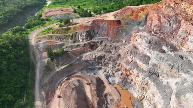 Drone perspective of open-pit mining operations showing dramatic geological changes, forest fragmentation, and the growing need for sustainable land management practices. 4k.
