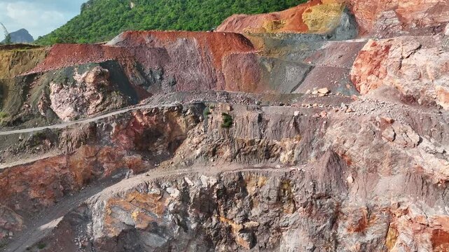 Aerial view of an open-pit stone quarry showing large-scale resource extraction, exposed geological layers, and the environmental impact of mining activities on natural landscapes. 4k.
