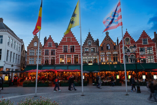 Historic guild houses line a cobbled square with flags