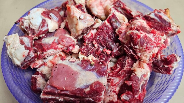 Raw, cut-up beef ribs placed on a purple plastic tray.