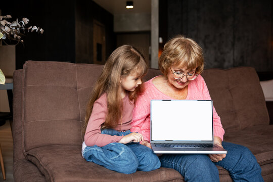 Grandmother and granddaughter using laptop with blank screen