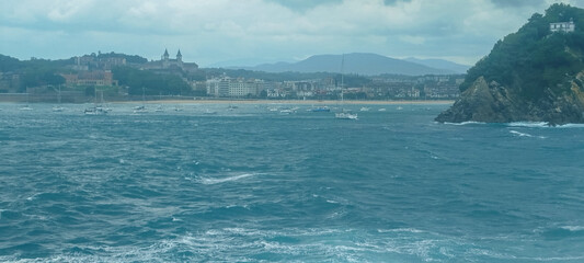 Fototapeta premium Vista panorámica de la bahía y la costa marítima bajo cielo nublado en San Sebastián, España.