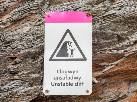 unstable cliff danger of falling rocks sign on beach in Wales UK Clogwyn Ansafadwy