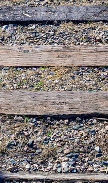Old weathered wooden railroad ties laid on a layer of gravel railway ballast