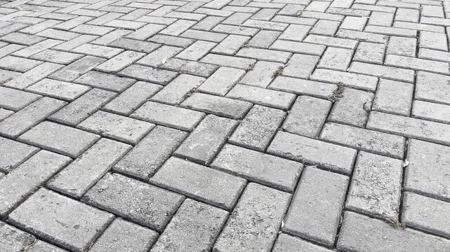 Grey interlocking paving blocks with herringbone pattern texture