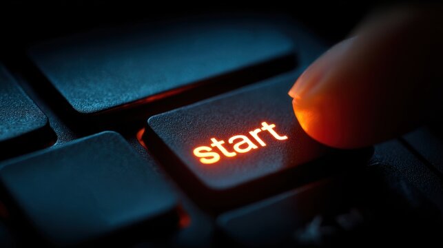 Finger pressing glowing start button on computer keyboard. Perfect for technology and business startup.