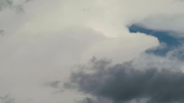 Time lapse with dense white clouds shift rapidly across the sky as a storm approaches during the late afternoon