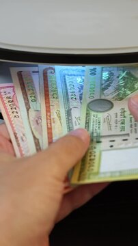 Examination of nepalese rupee (NPR) cash money with UV counterfeit detector. Concept of authenticity check, fight against counterfeiting of banknotes, anti fraud measures in Nepal. Close up view.