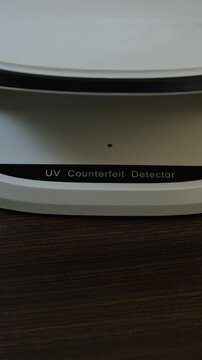 Examination of belarussian ruble (BYN) cash money with UV counterfeit detector. Concept of authenticity check, fight against counterfeiting of banknotes, anti fraud measures in Belarus. Close up view.