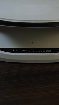 Examination of Cambodian Riel (KHR) cash money with UV counterfeit detector. Concept of authenticity check, fight against counterfeiting of banknotes, anti fraud measures in Cambodia. Close up view.