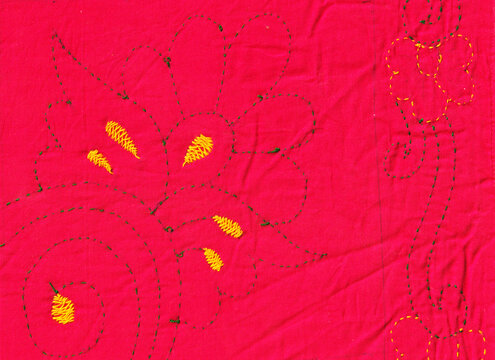 Vintage Nakshi Kantha traditional Bangladeshi hand-embroidered quilt texture with red and black running stitches and floral motifs on beige cotton fabric