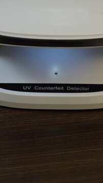 Examination of Azerbaijanian Manat cash money with UV counterfeit detector. Concept of authenticity check, fight against counterfeiting of banknotes, anti fraud measures in Azerbaijan. Close up view.