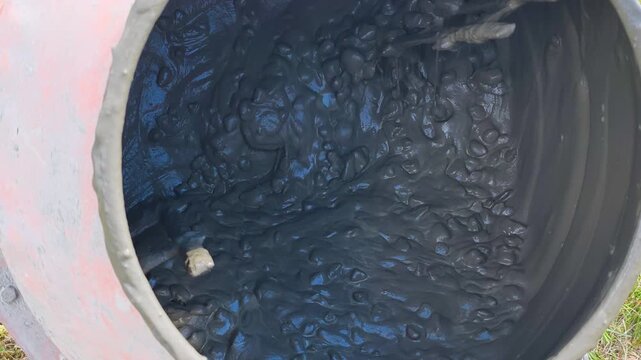Mixing process shows wet concrete swirling inside industrial mixer drum at construction site. Mixing process creates smooth texture, essential step for strong building materials and quality.