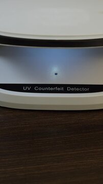 Examination of Mongolian Tugrik (MNT) cash money with UV counterfeit detector. Concept of authenticity check, fight against counterfeiting of banknotes, anti fraud measures in Mongolia. Close up view.